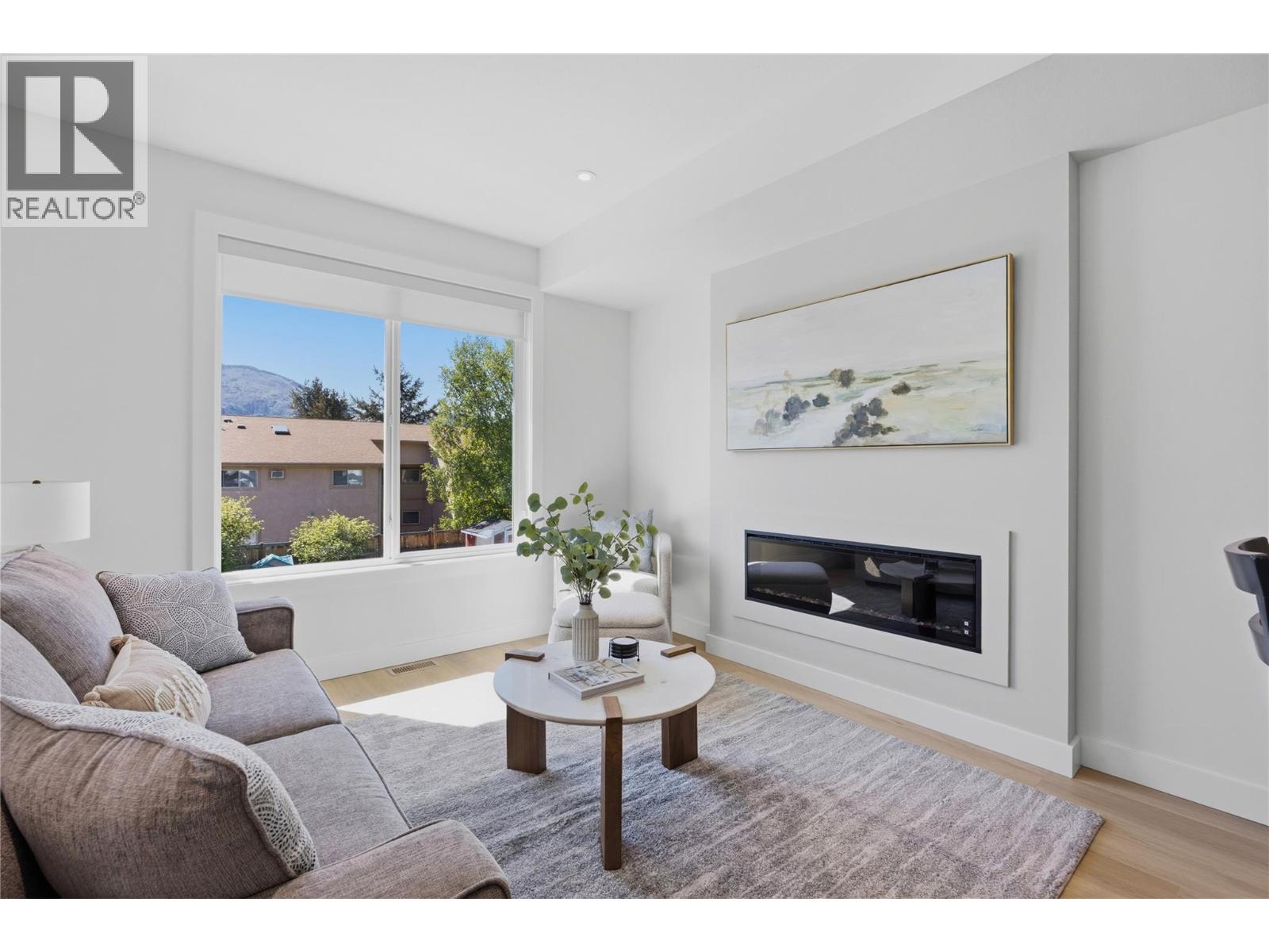 Representative listing media for Unit 101 at 143 Green Avenue, Penticton — bright living room with fireplace