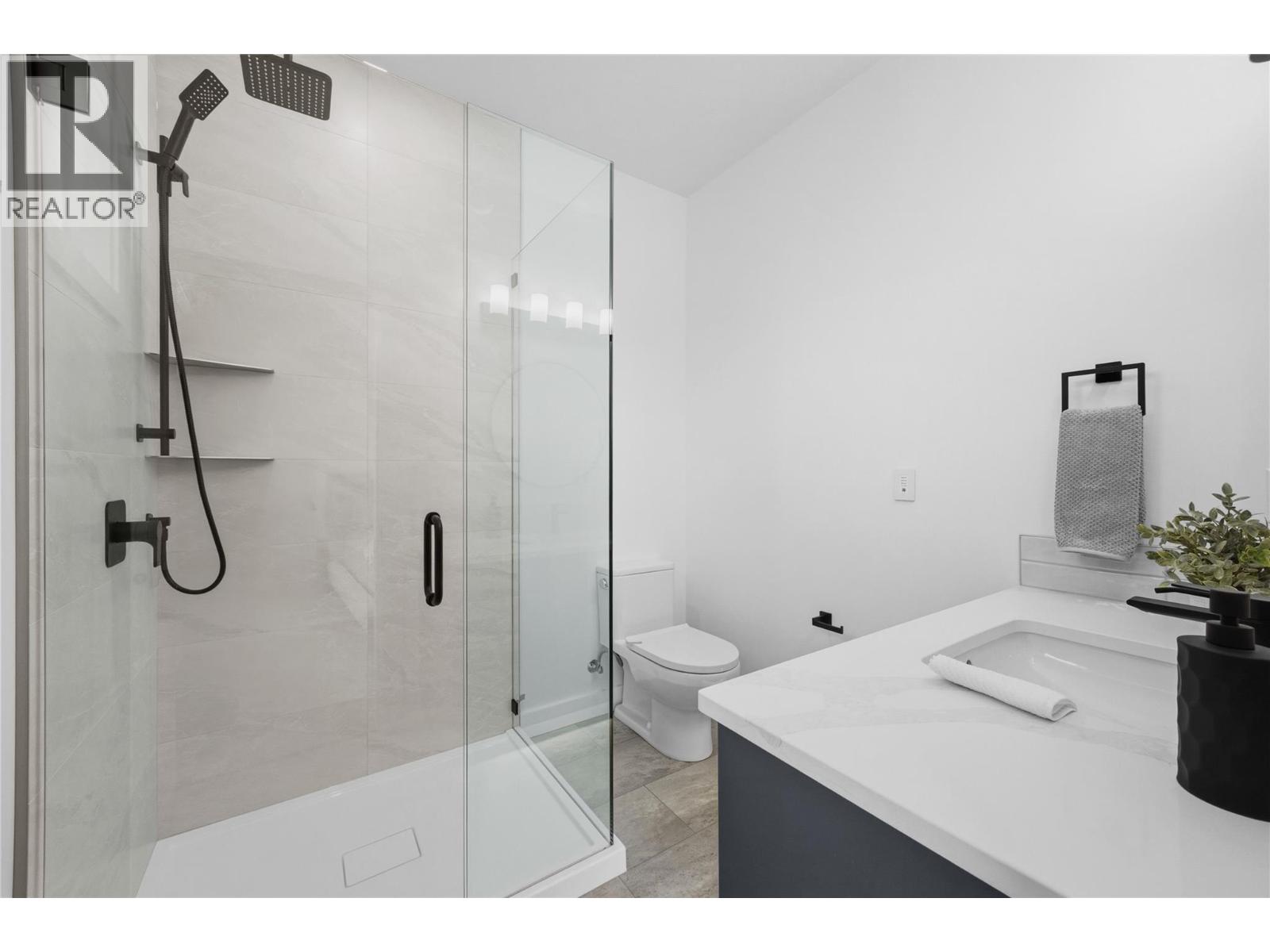 Representative listing media for Unit 102 at 143 Green Avenue, Penticton — full bathroom with glass shower
