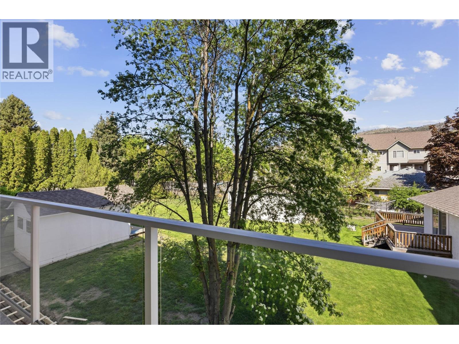 Representative listing media for Unit 102 at 143 Green Avenue, Penticton — fenced backyard and mature trees