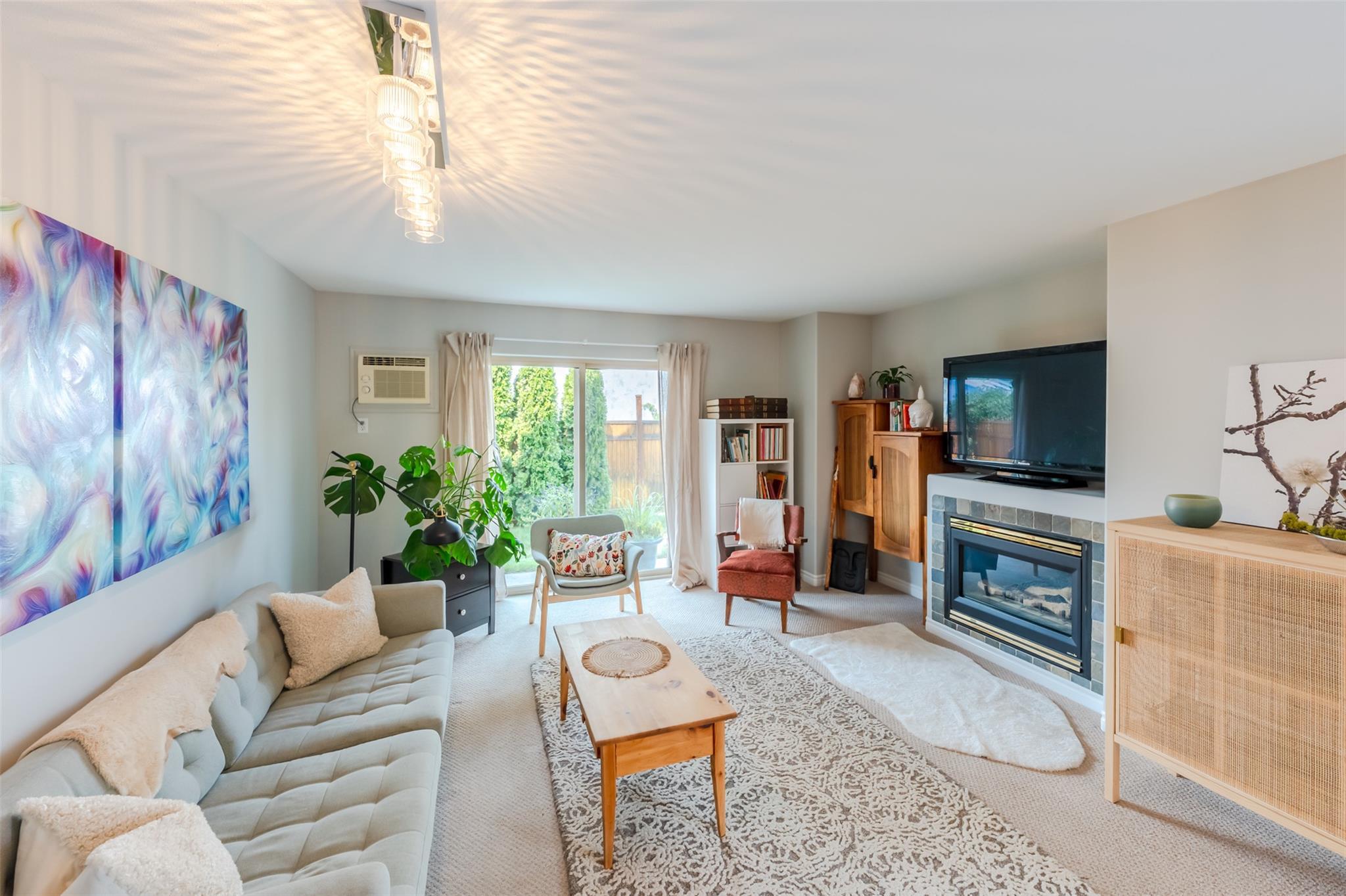 Bright living room with fireplace and patio doors in Unit 101.