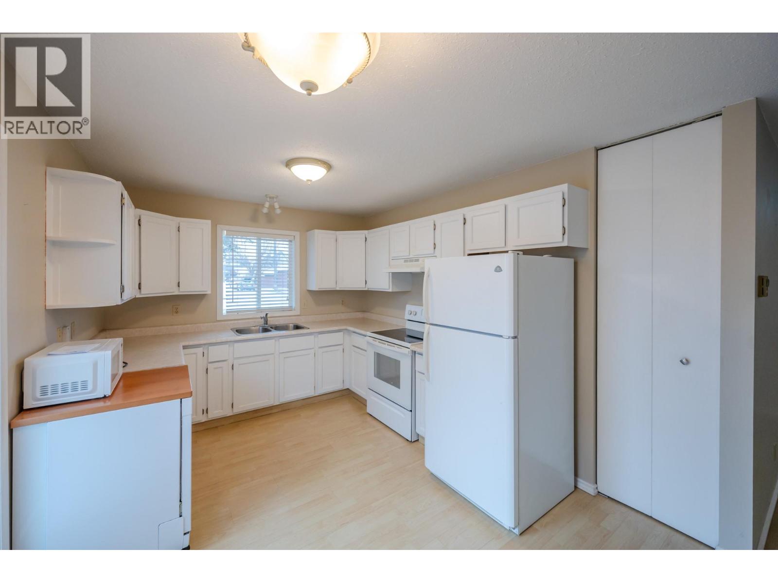 White U-shaped kitchen in Unit 101 at 601 Wade Avenue W, Penticton