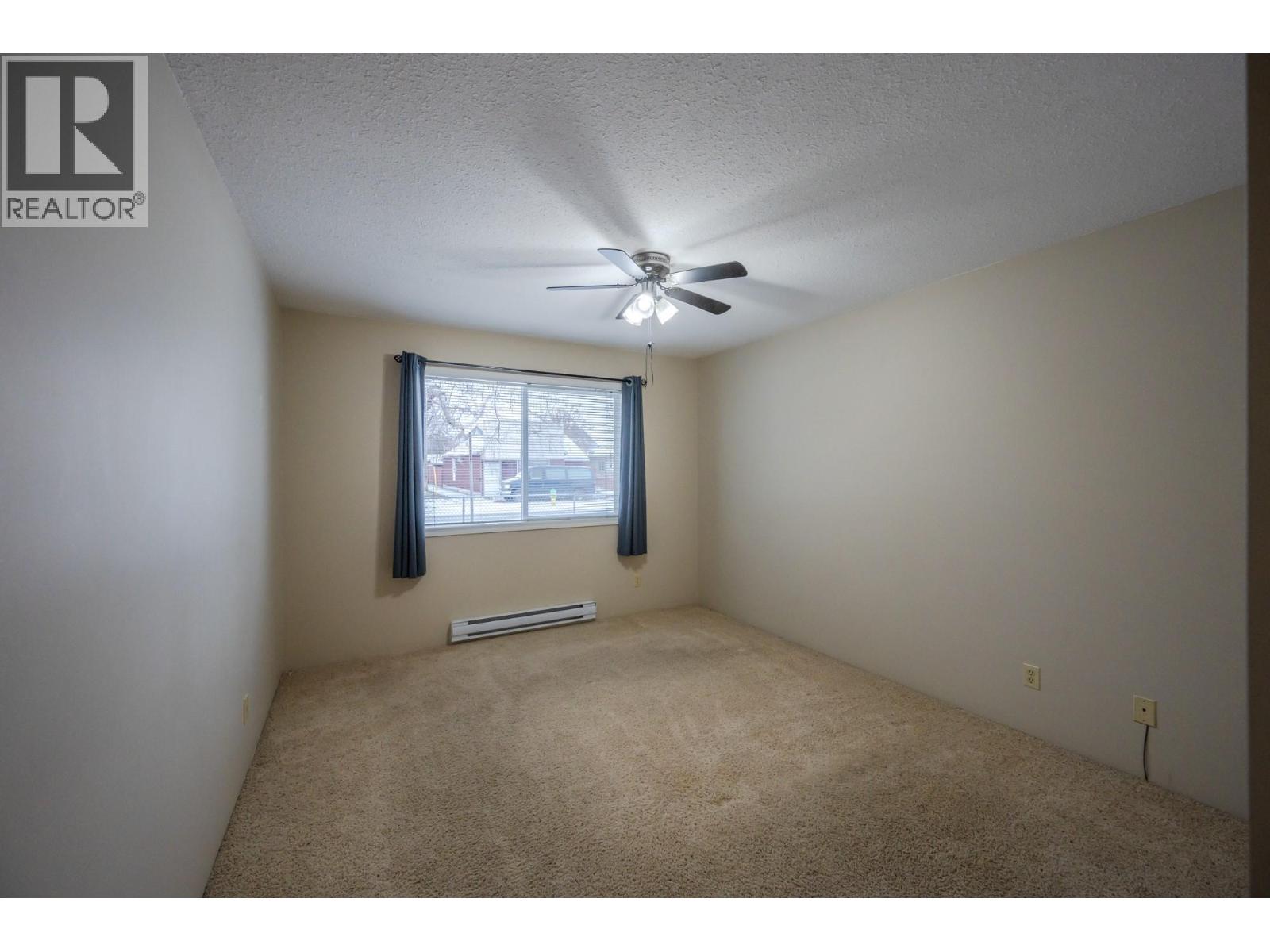 Carpeted primary bedroom in Unit 101 at 601 Wade Avenue W, Penticton