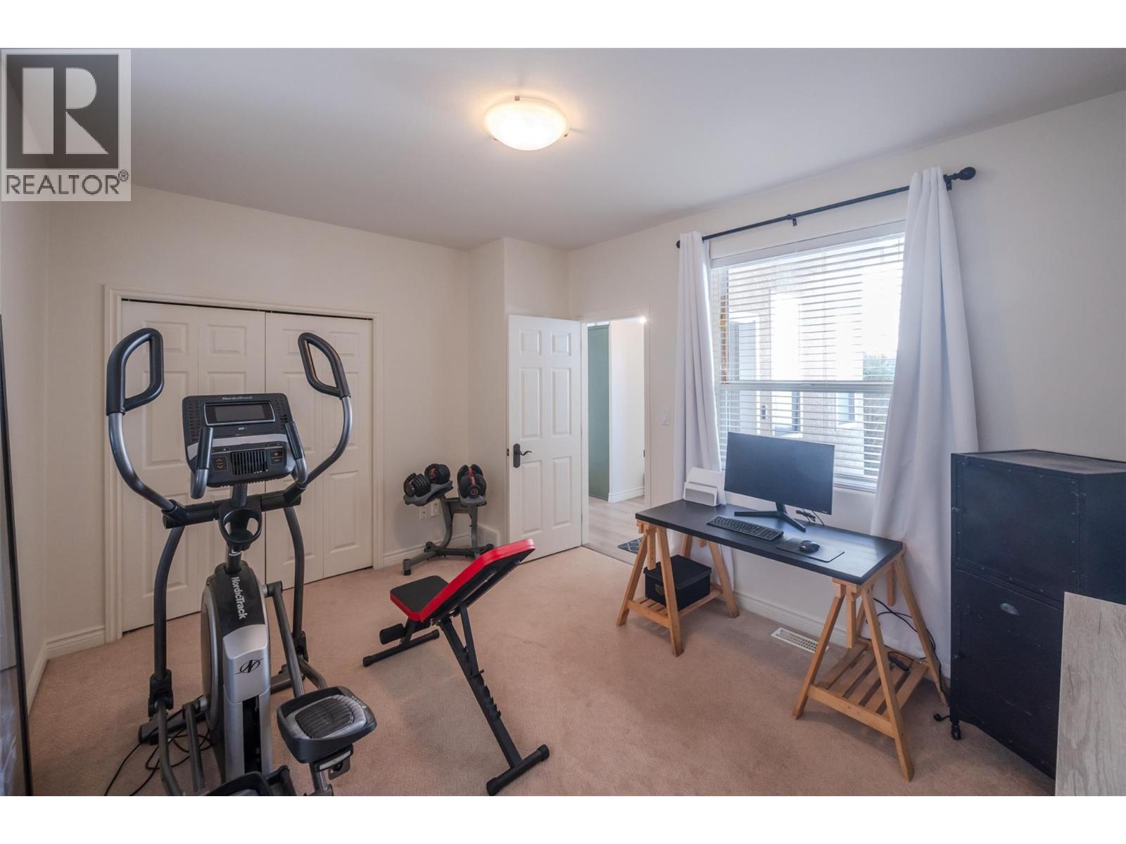 Flexible second bedroom staged as an office and home gym.