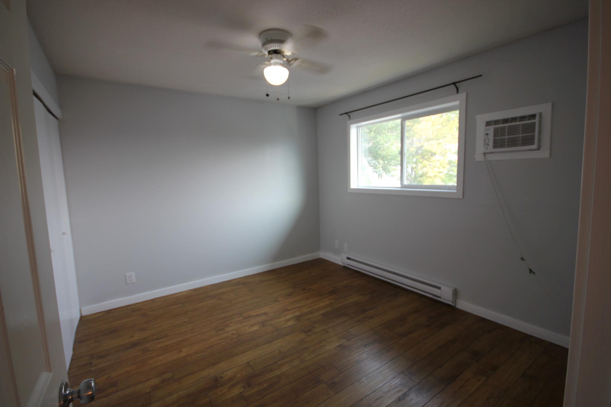 Bedroom with a window and hardwood flooring in Unit 104.