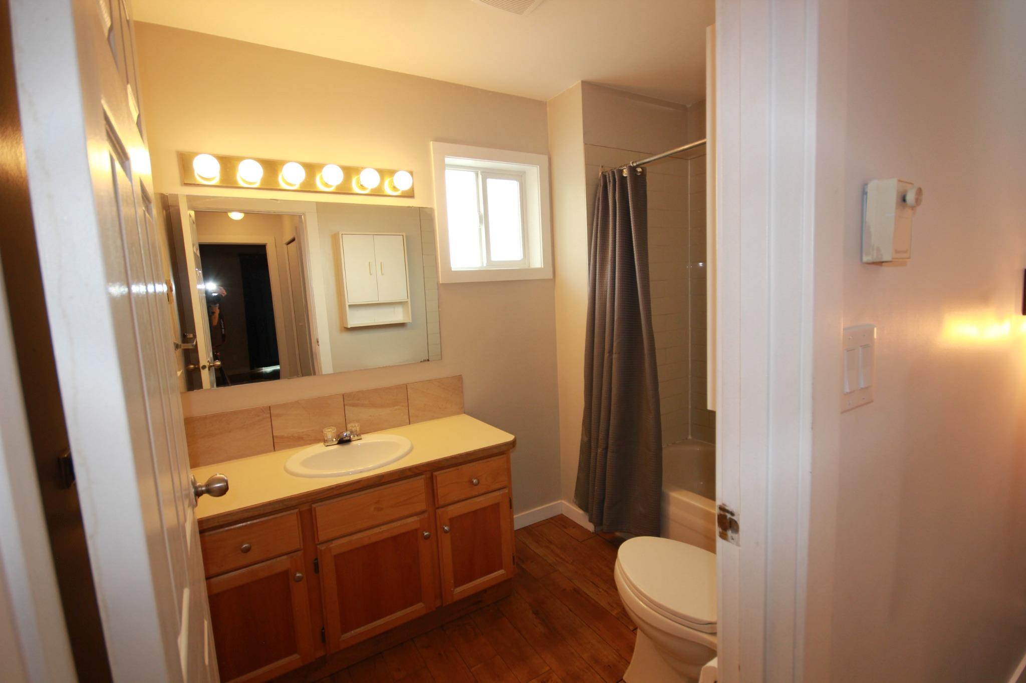 Full bathroom with tub and wood vanity in Unit 104.