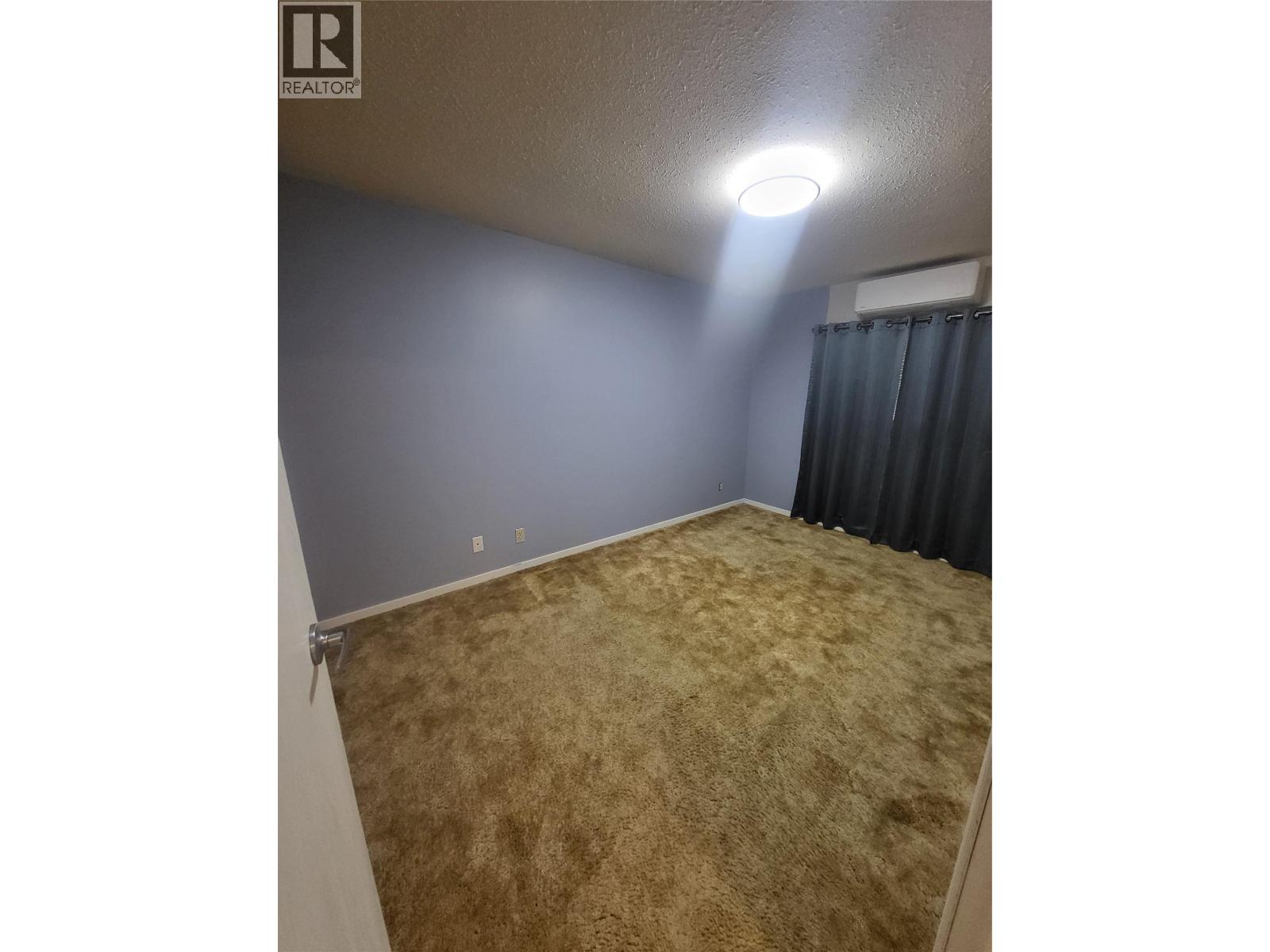 Carpeted bedroom in Unit 105 at 601 Wade Avenue W, Penticton