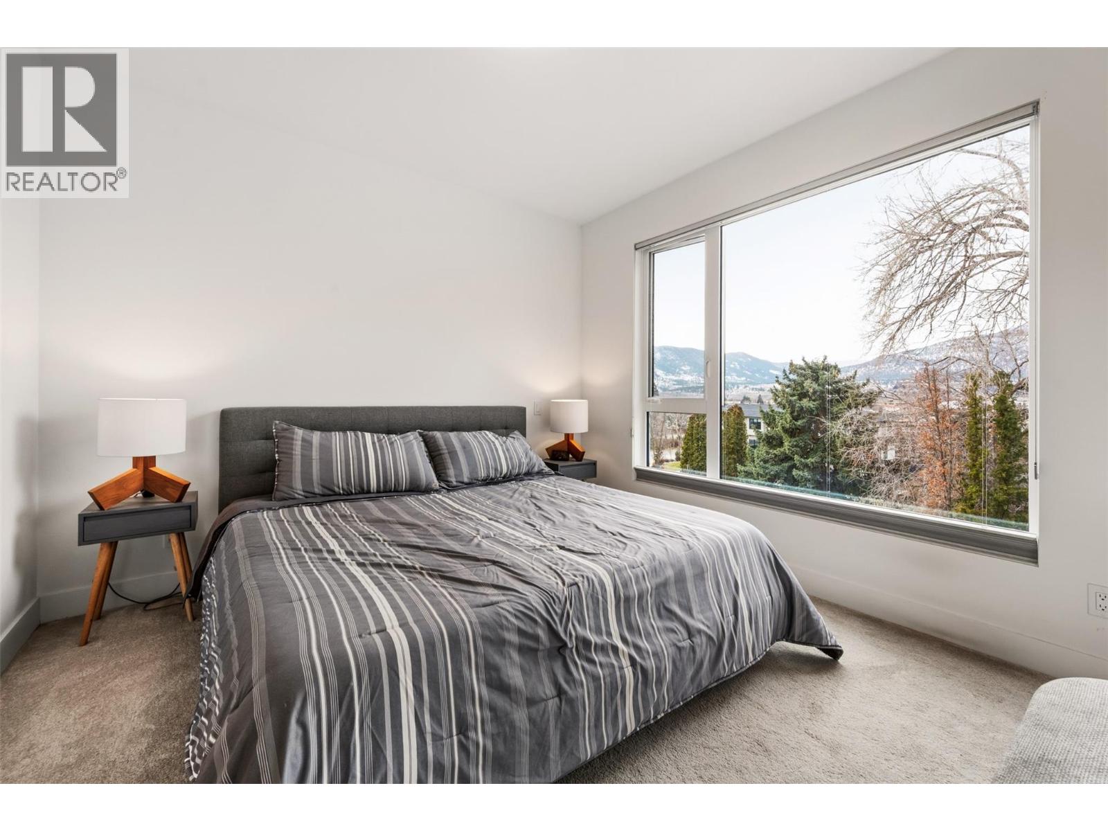 108 555 Wade Avenue E, Penticton — primary bedroom with mountain outlook