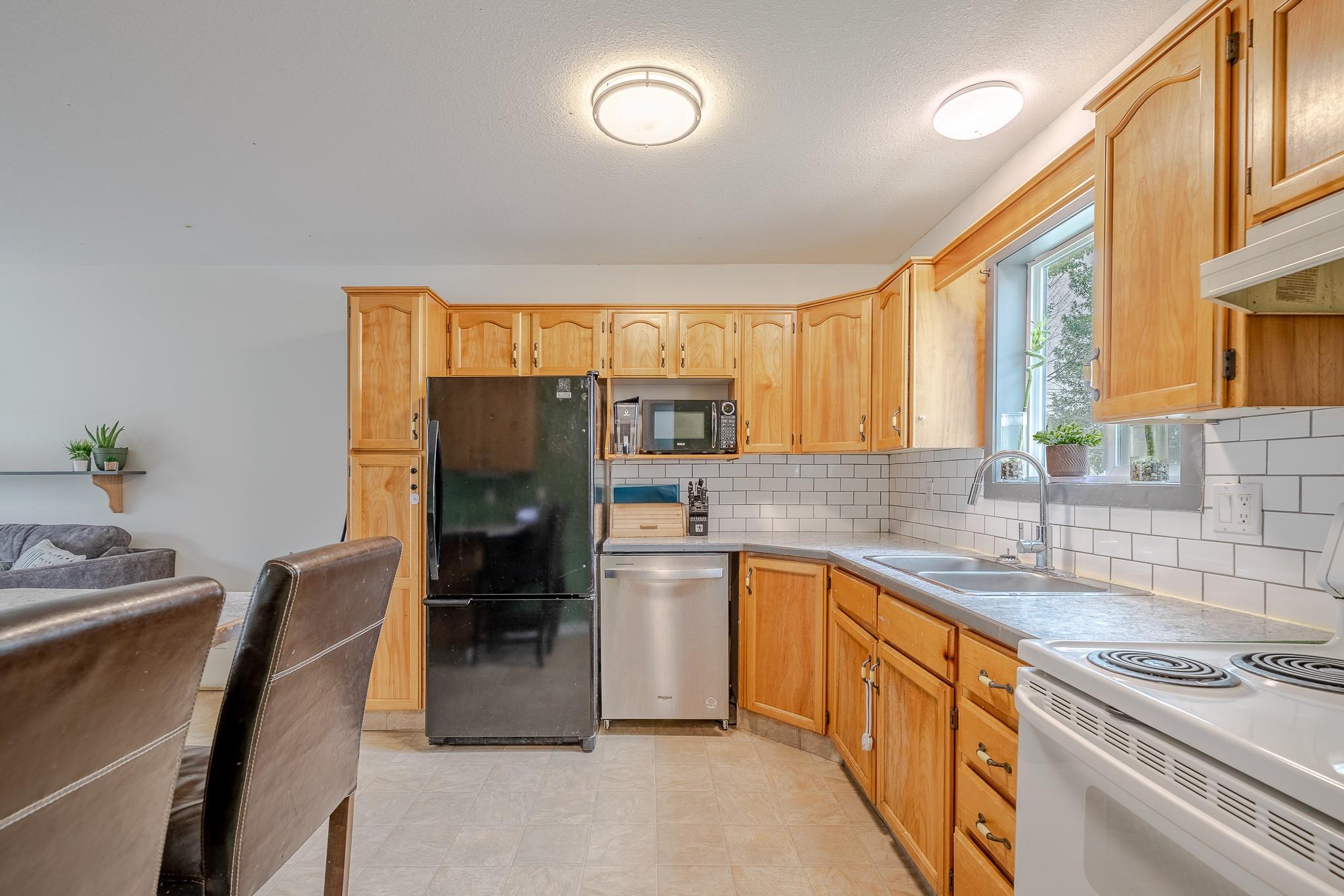 Updated kitchen with wood cabinetry and stainless dishwasher in Unit 124.
