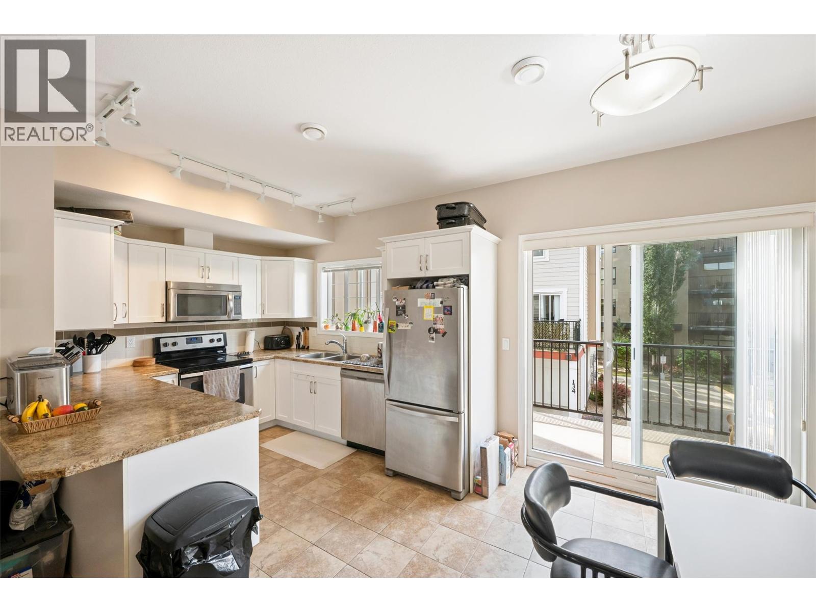 128 3363 Wilson Street, Penticton — kitchen and dining area with balcony access