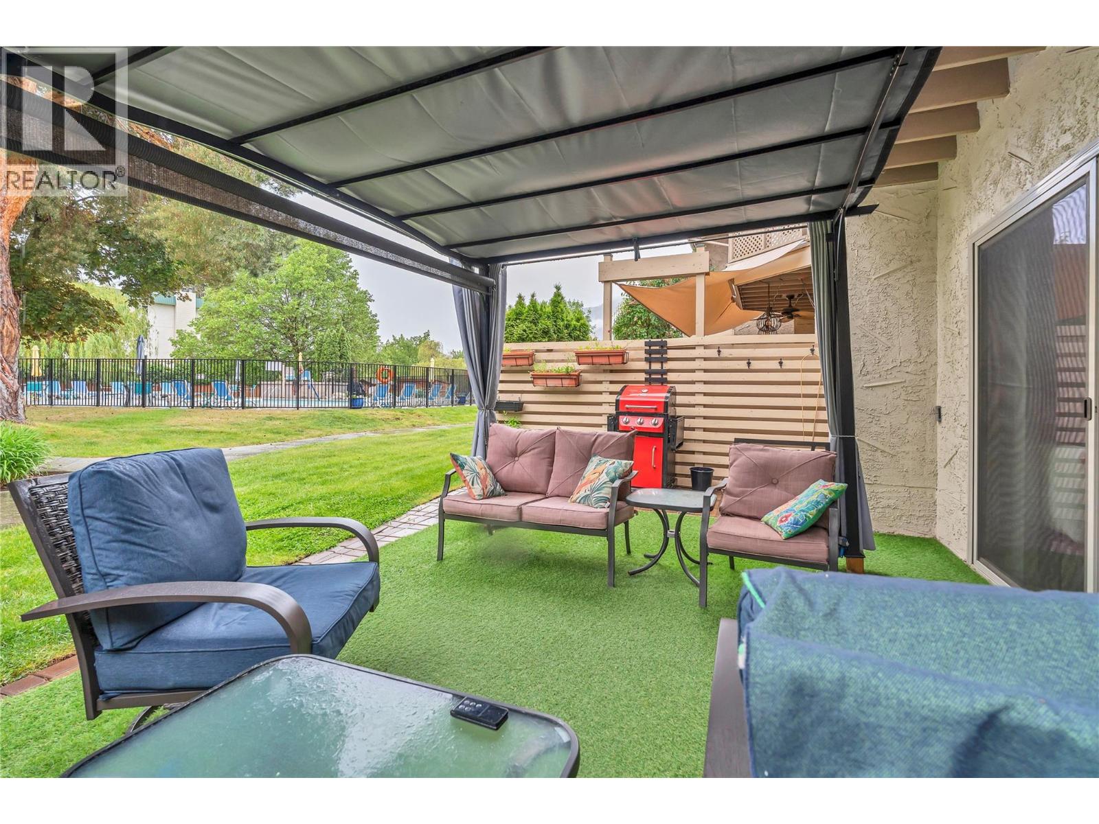 Unit 13 at Skaha Village, 310 Yorkton Avenue, Penticton — covered backyard patio and greenspace