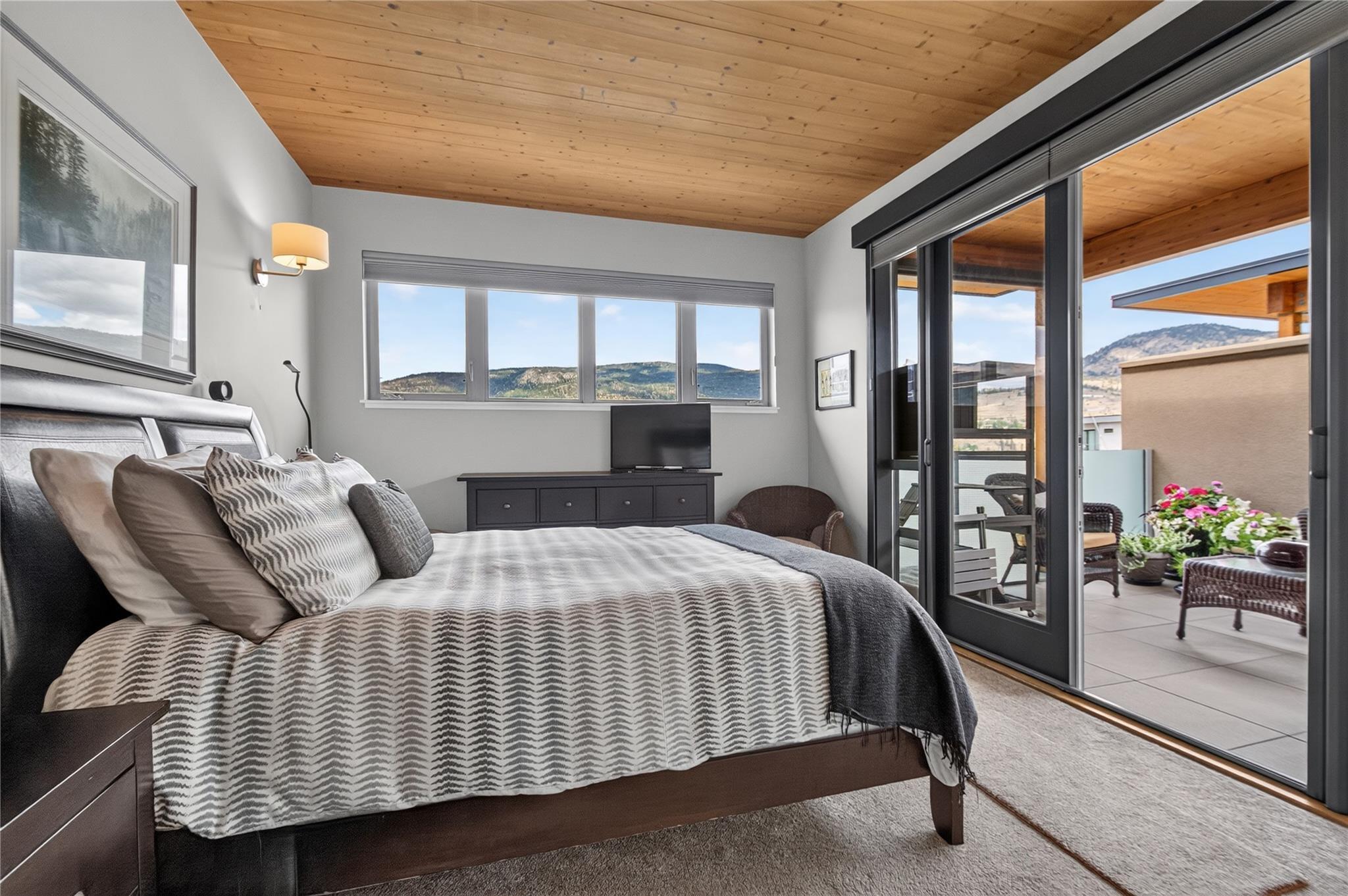 102-433 Churchill Avenue, Penticton — primary bedroom with wood ceiling and balcony access