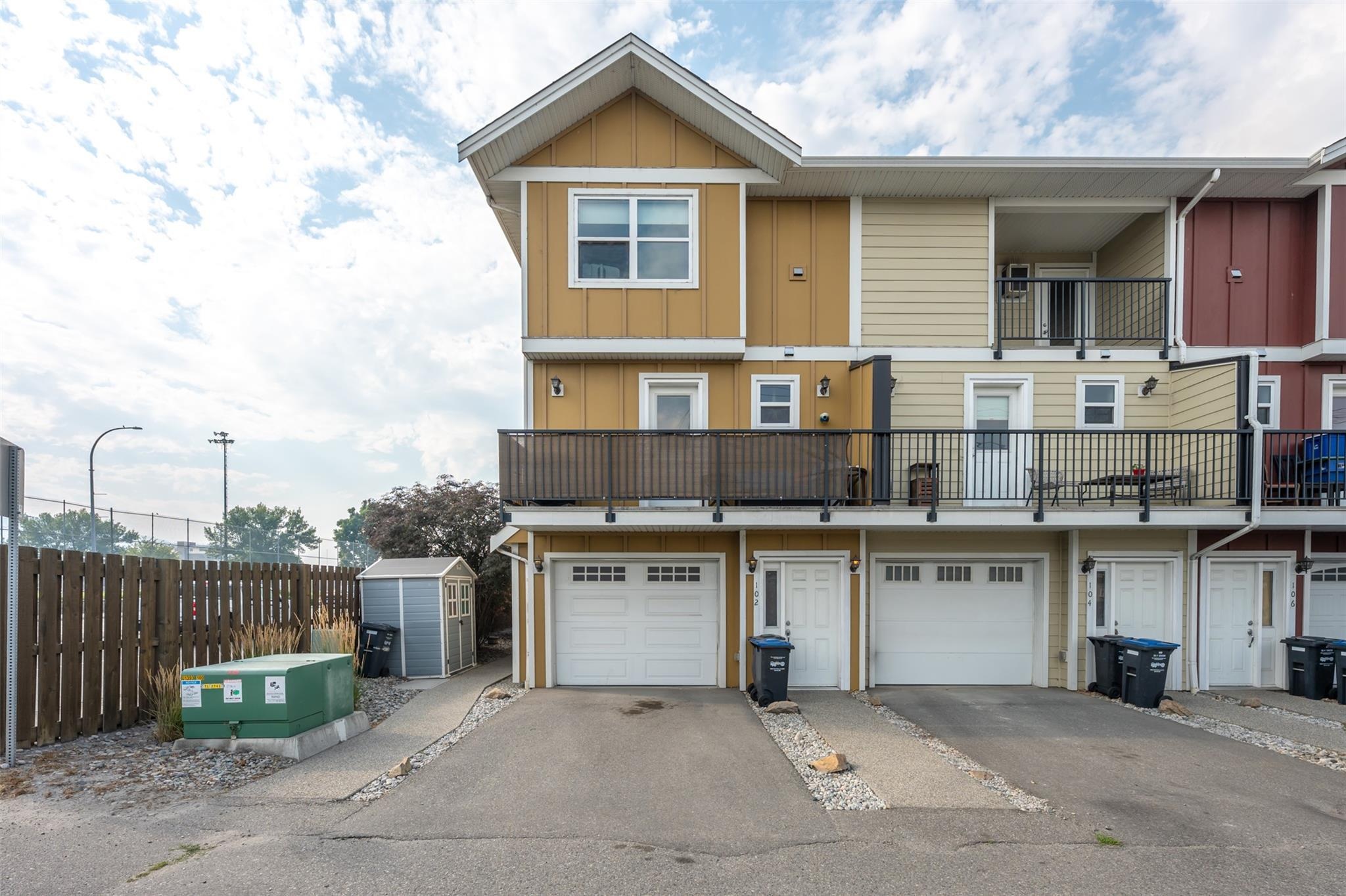Rear exterior with garage, balcony and designated parking at Unit 102.