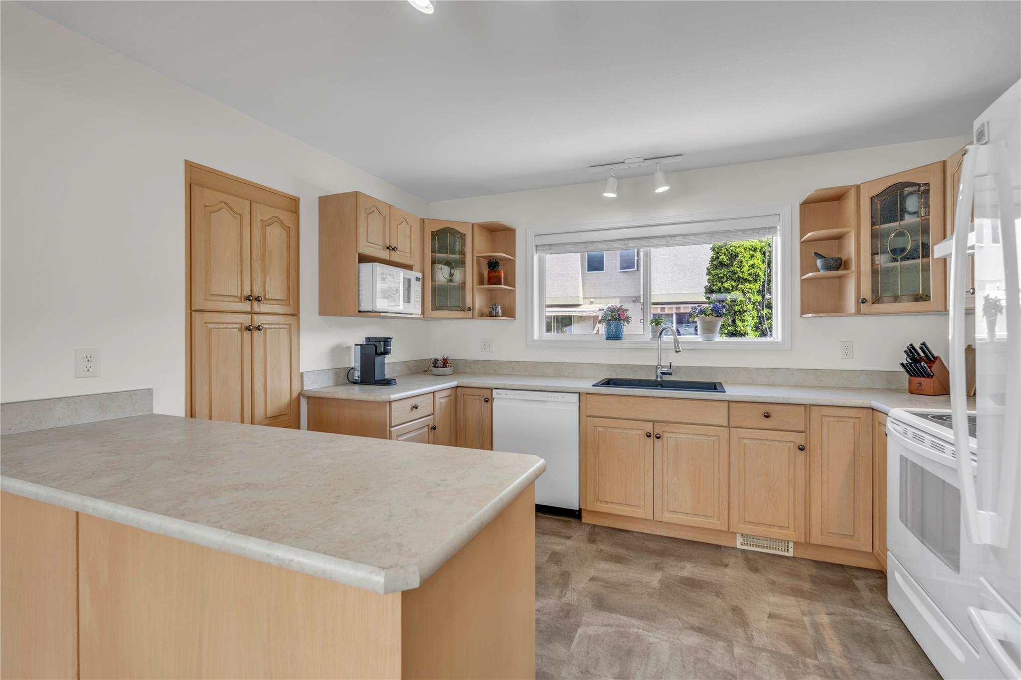 103 166 Green Avenue W, Penticton — kitchen with island, wood cabinetry and white appliances