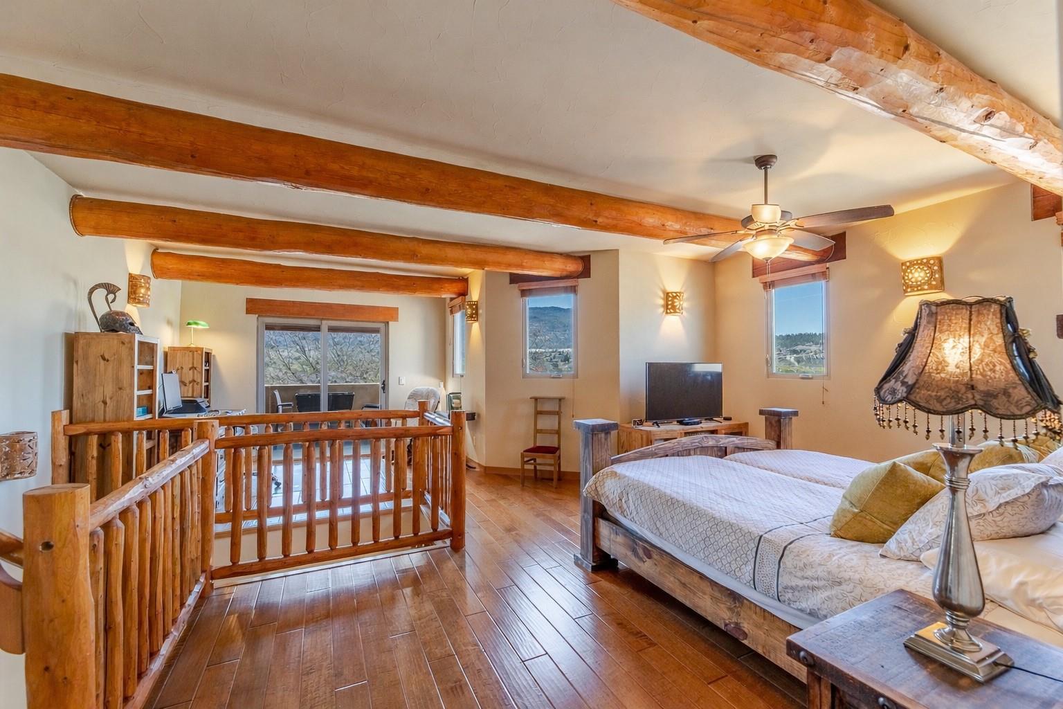 Primary bedroom with exposed beams and wood flooring at Unit 105.
