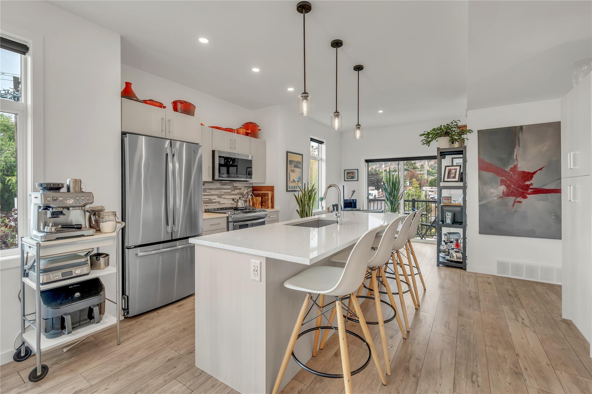 Open kitchen with quartz island and stainless appliances in Unit 115.