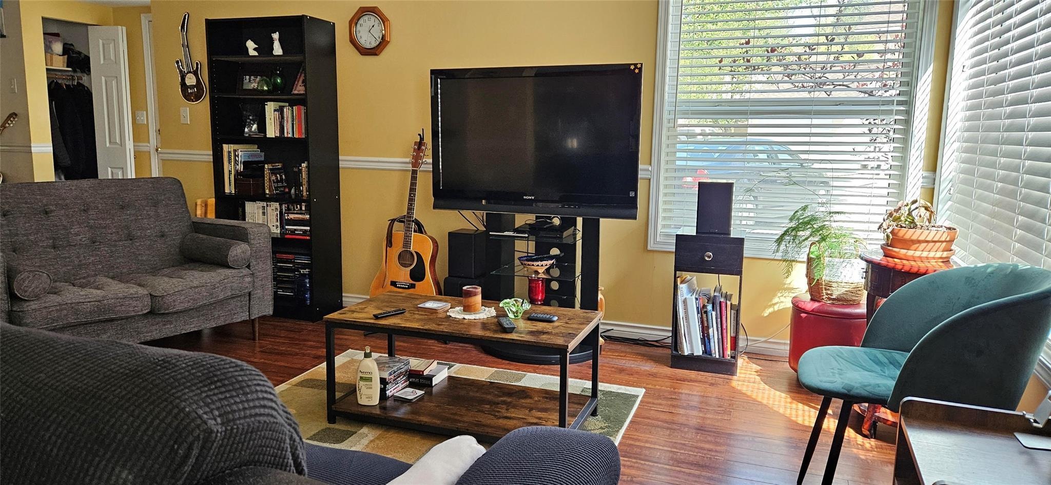 Living room with corner windows and wood-look flooring at Unit 119.