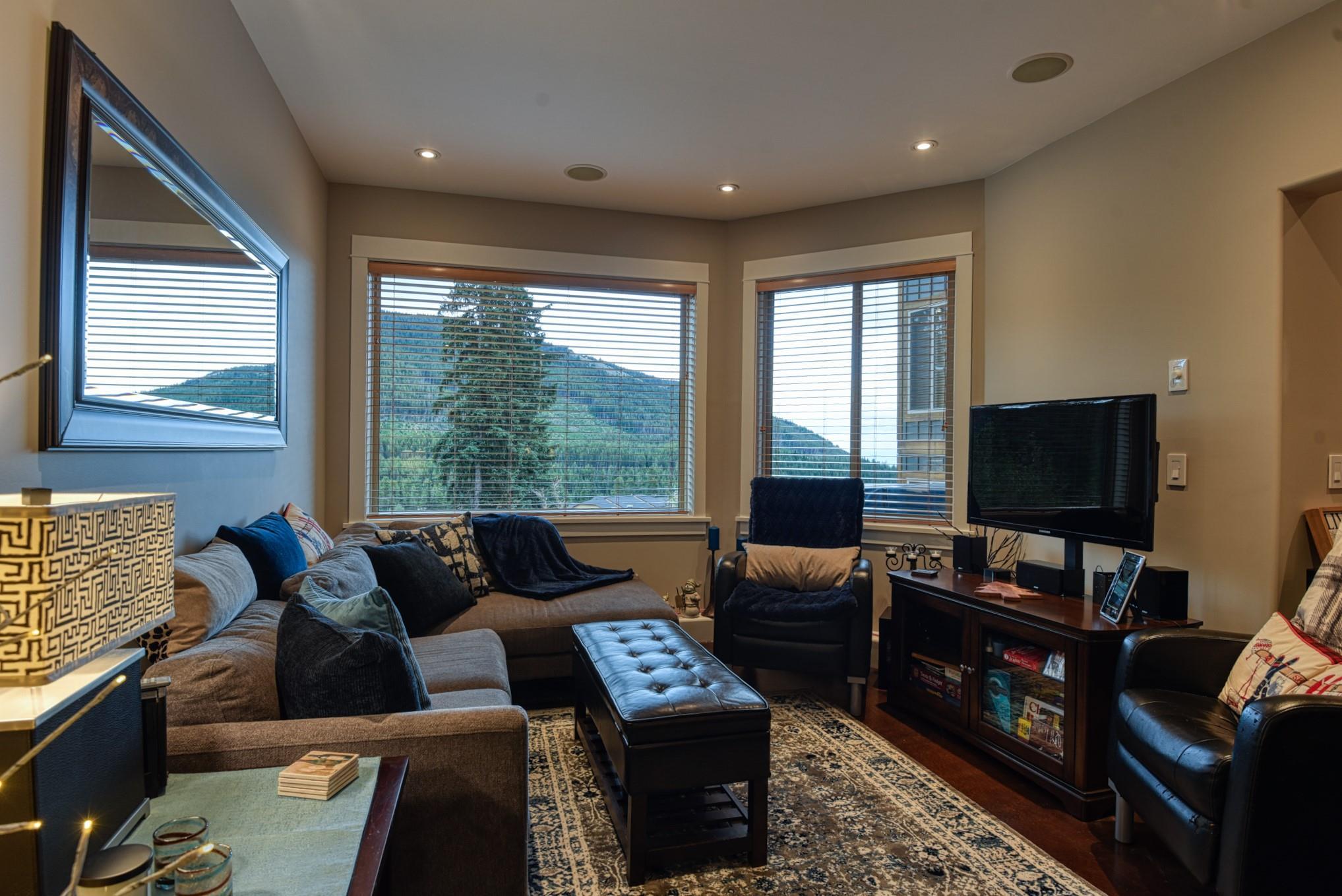Living room with large picture windows and propane stove at Unit 12 in Snowridge, Apex Mountain.