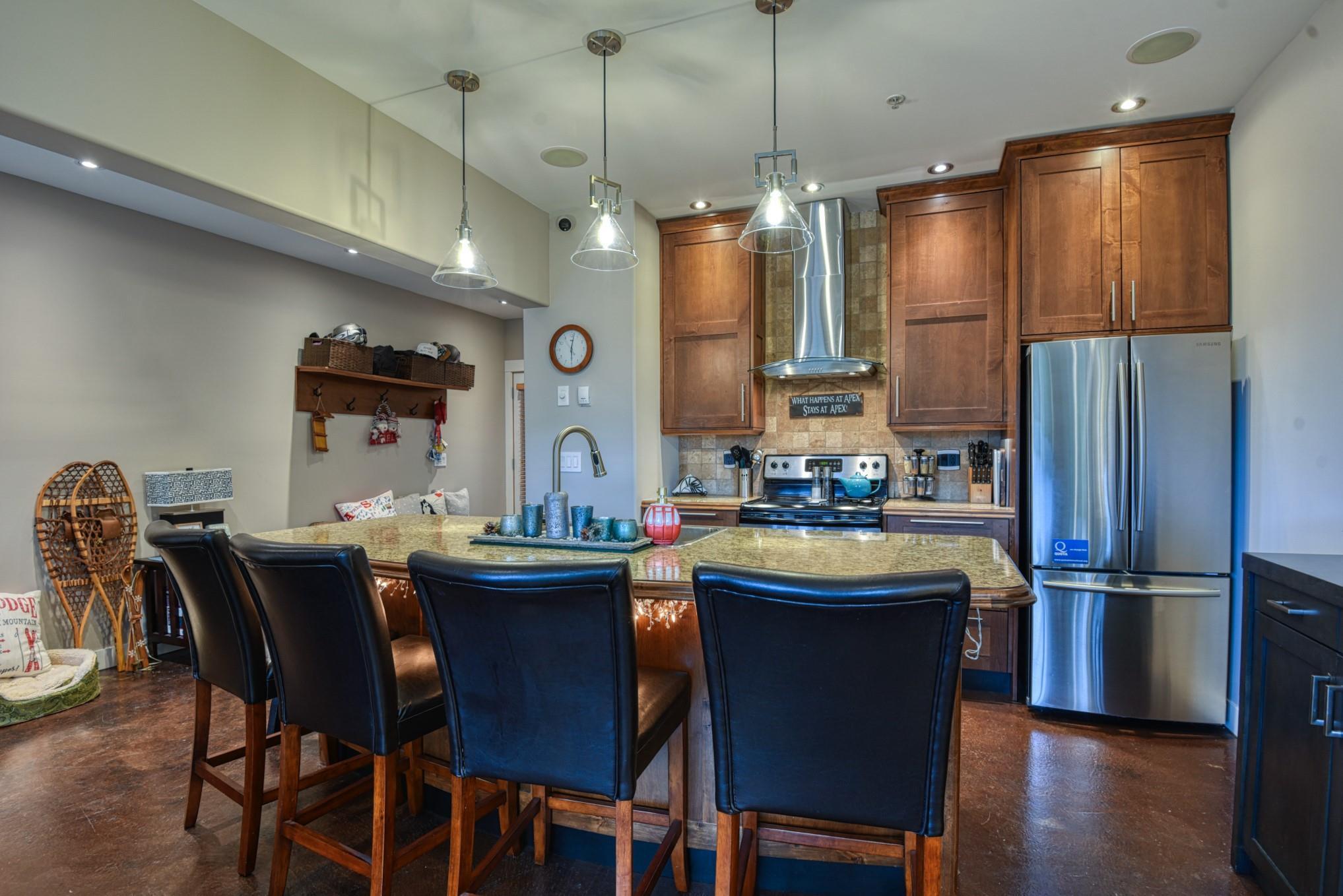 Kitchen with wood cabinetry, stainless appliances and breakfast-bar seating at Unit 12.
